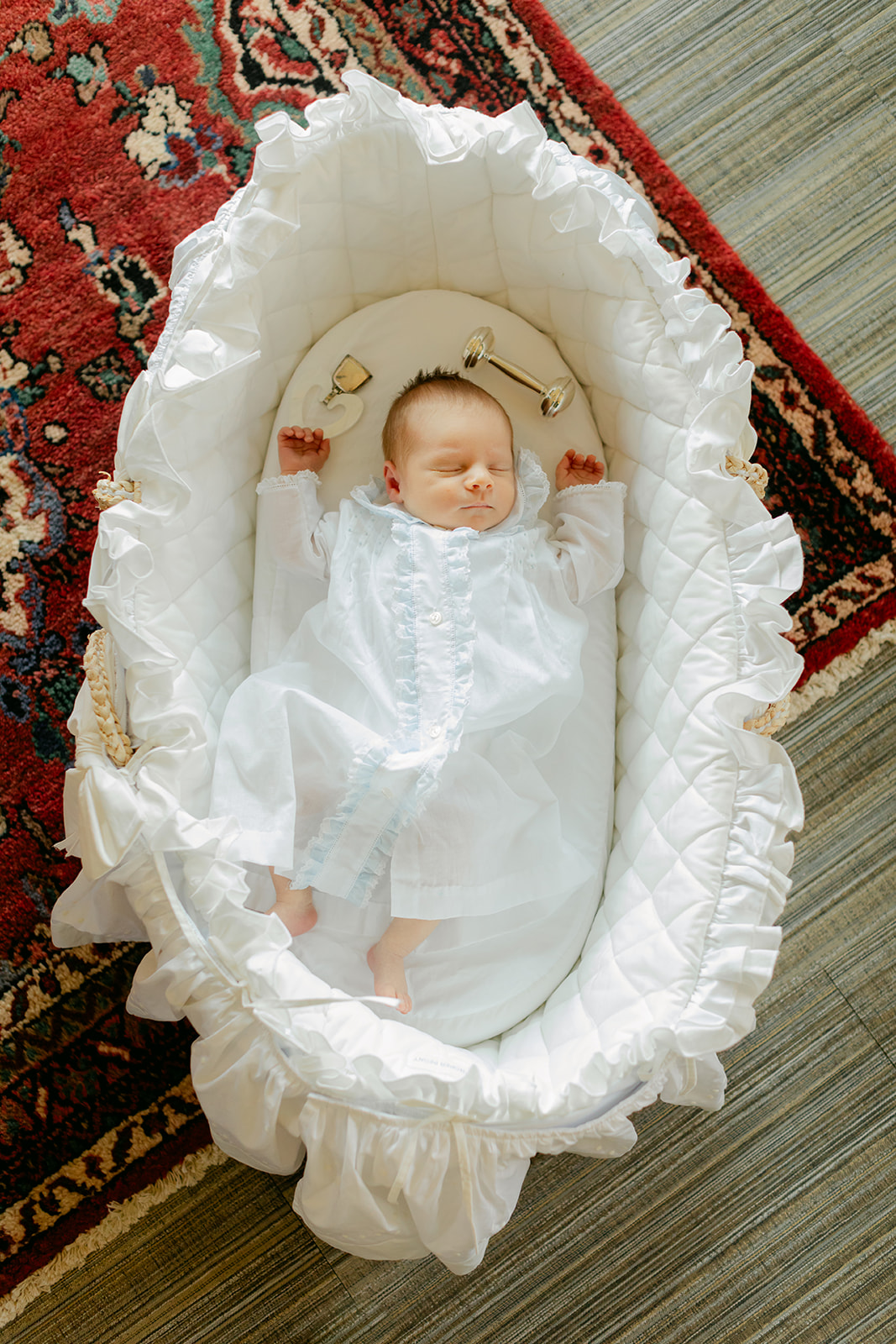 newborn baby boy in white outfit in bassinet