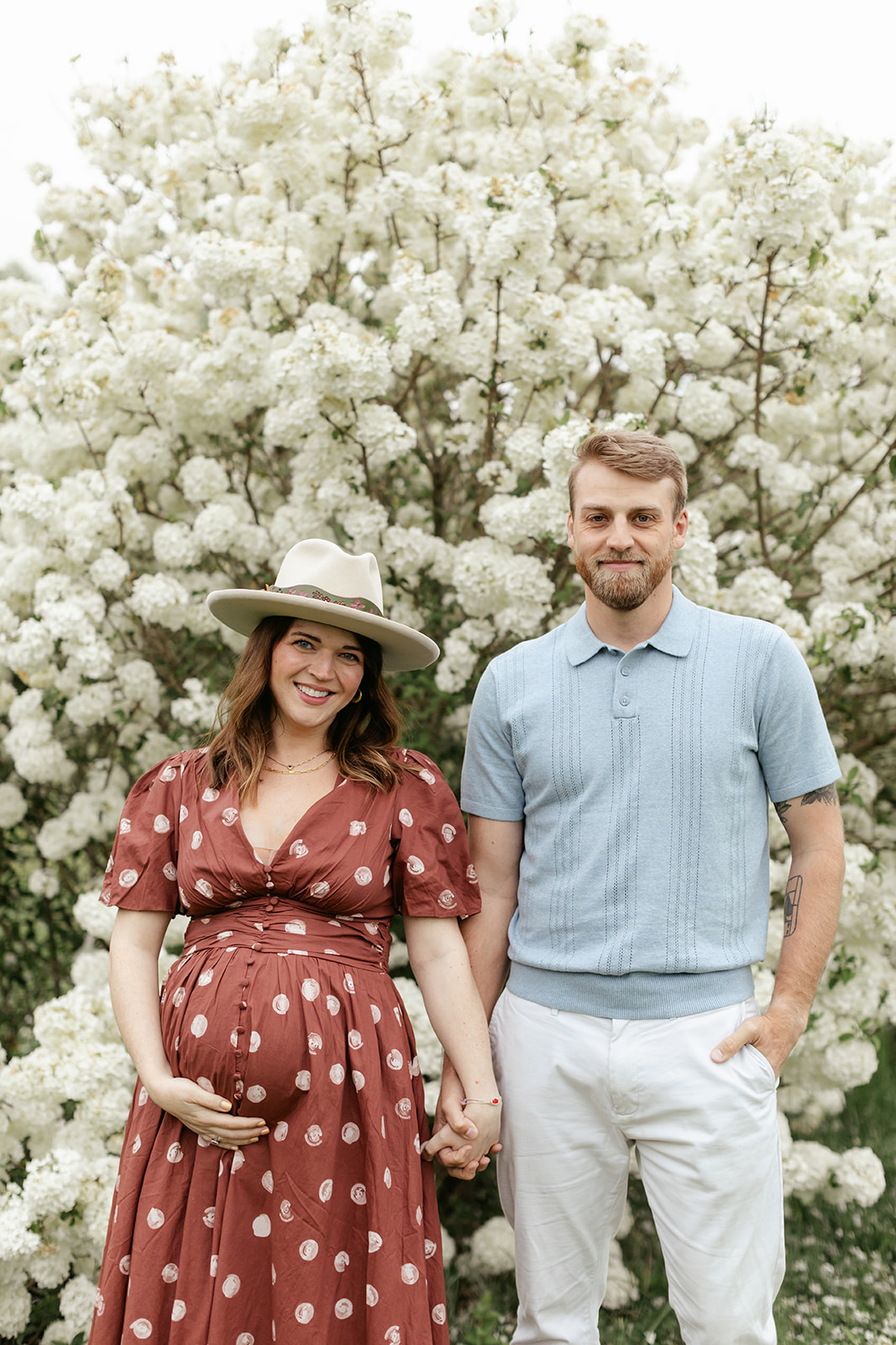 couple during maternity photos with flower bush