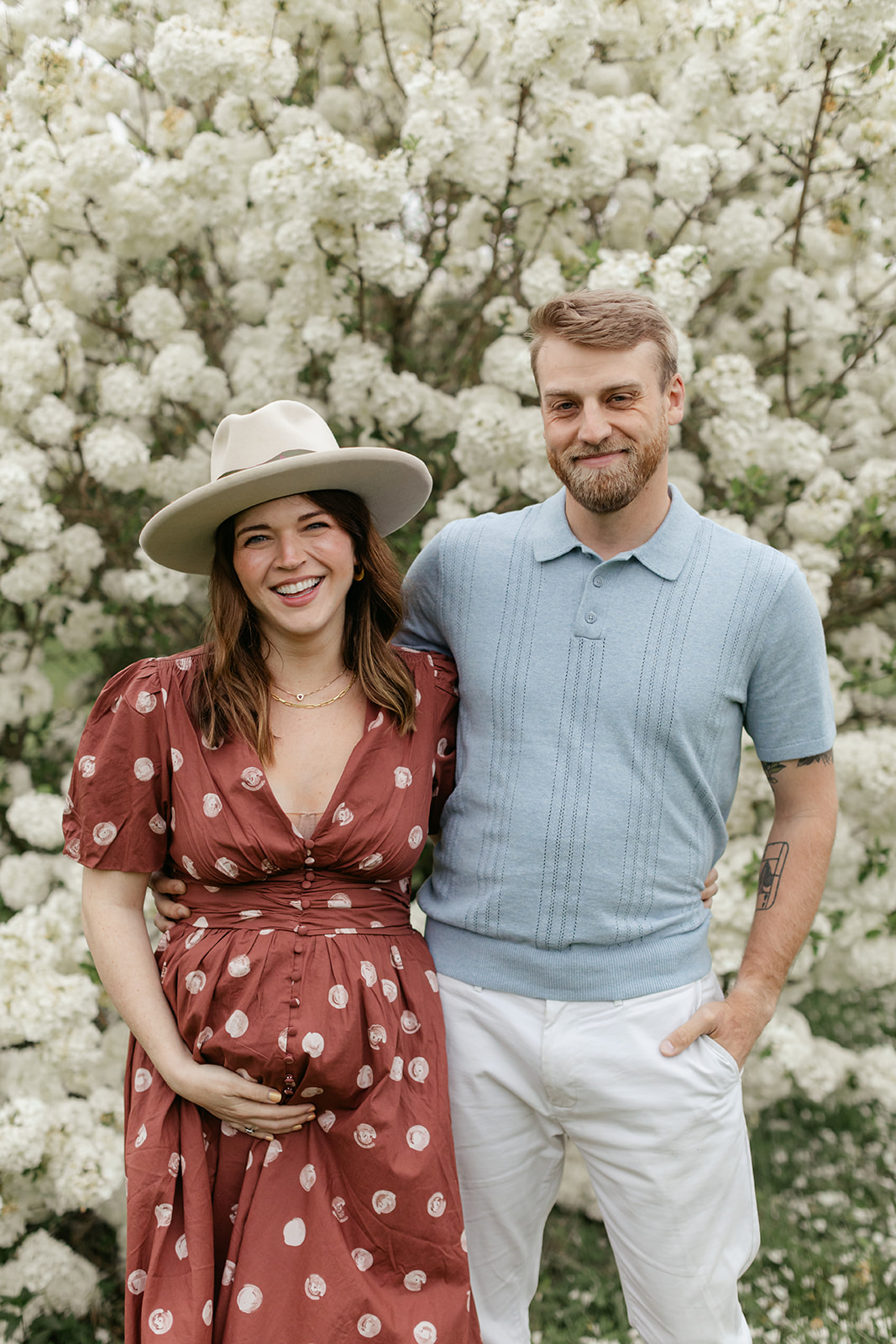 couple during maternity photos with flower bush