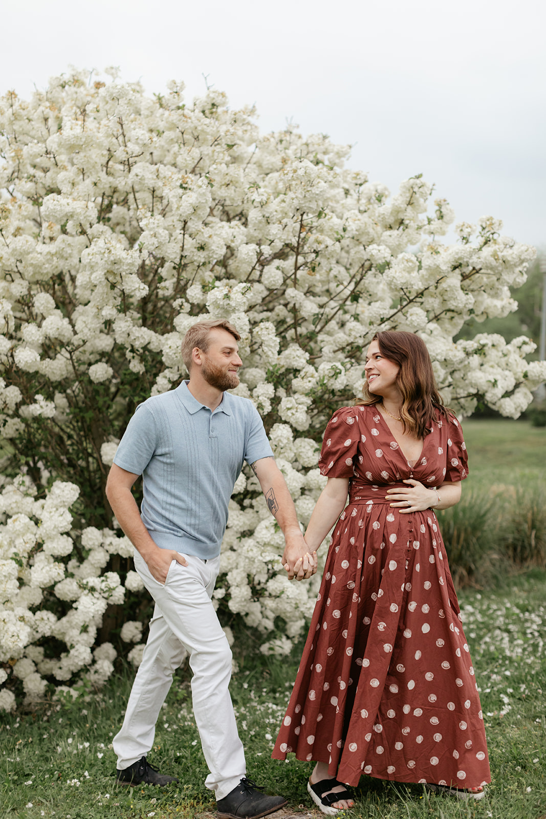 couple during maternity photos with flower bush