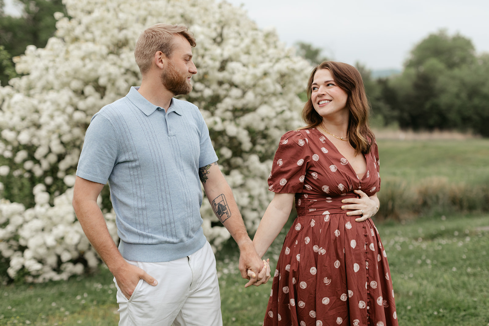 couple during maternity photos with flower bush