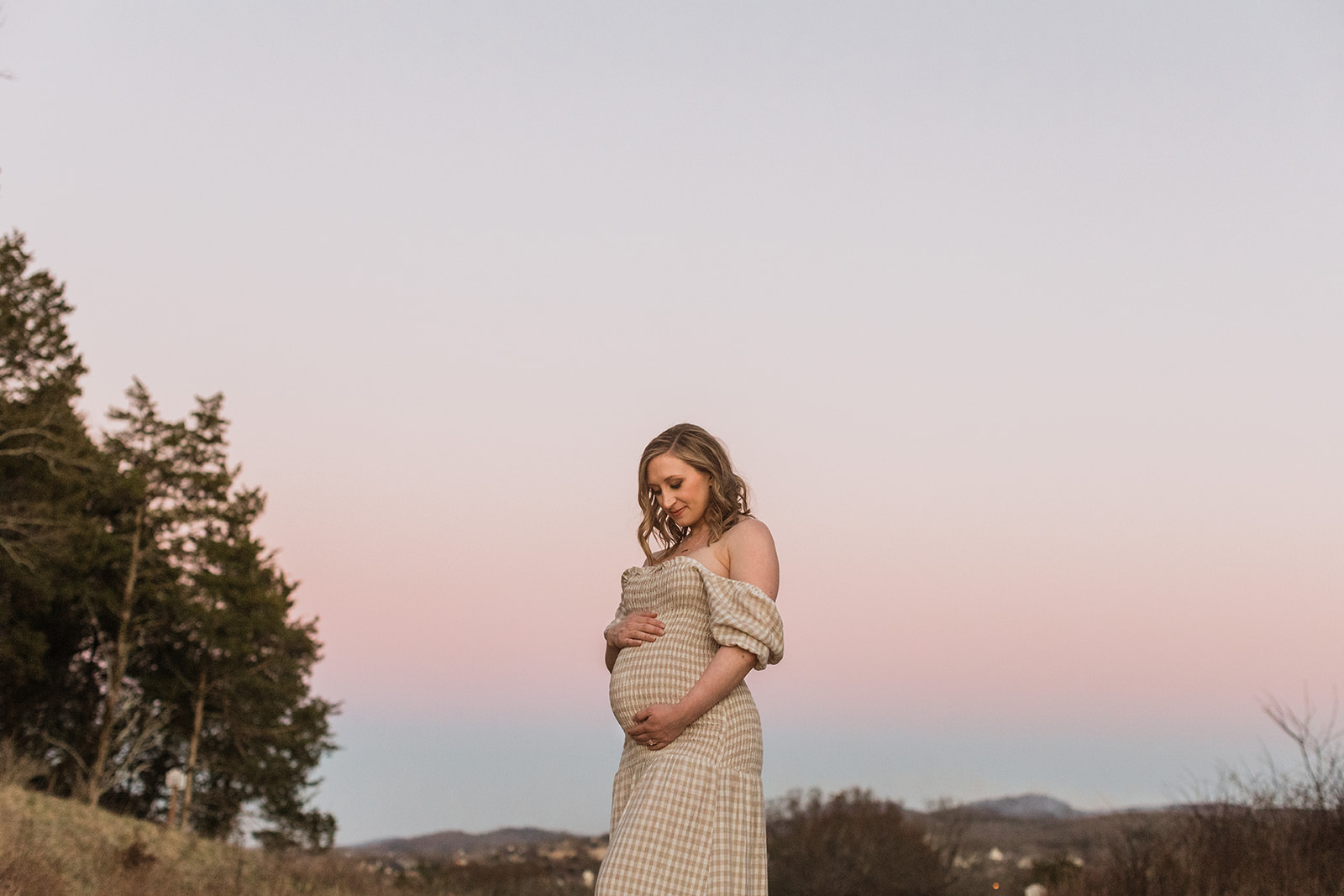expecting mama posing during sunset maternity session, pink skies