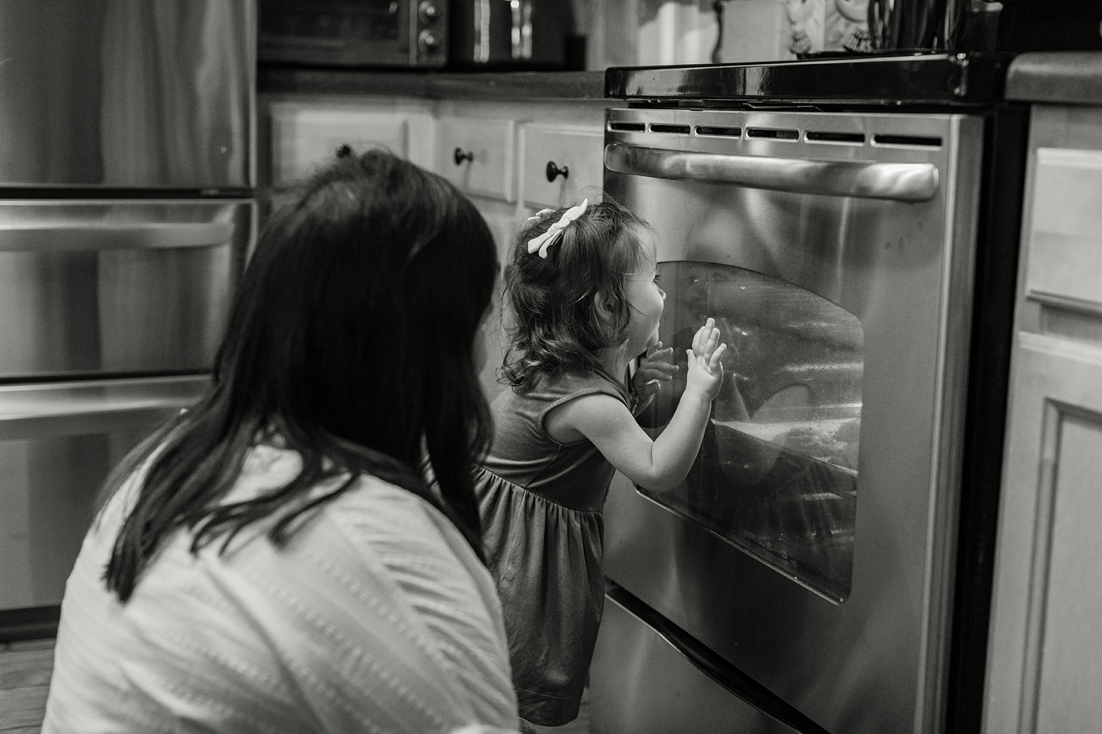 little girl looking in oven waiting for cookies to bake