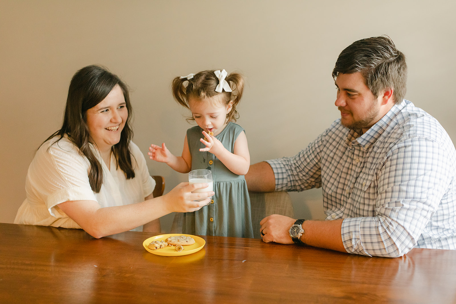 little girl drinking milk and cookies with parents