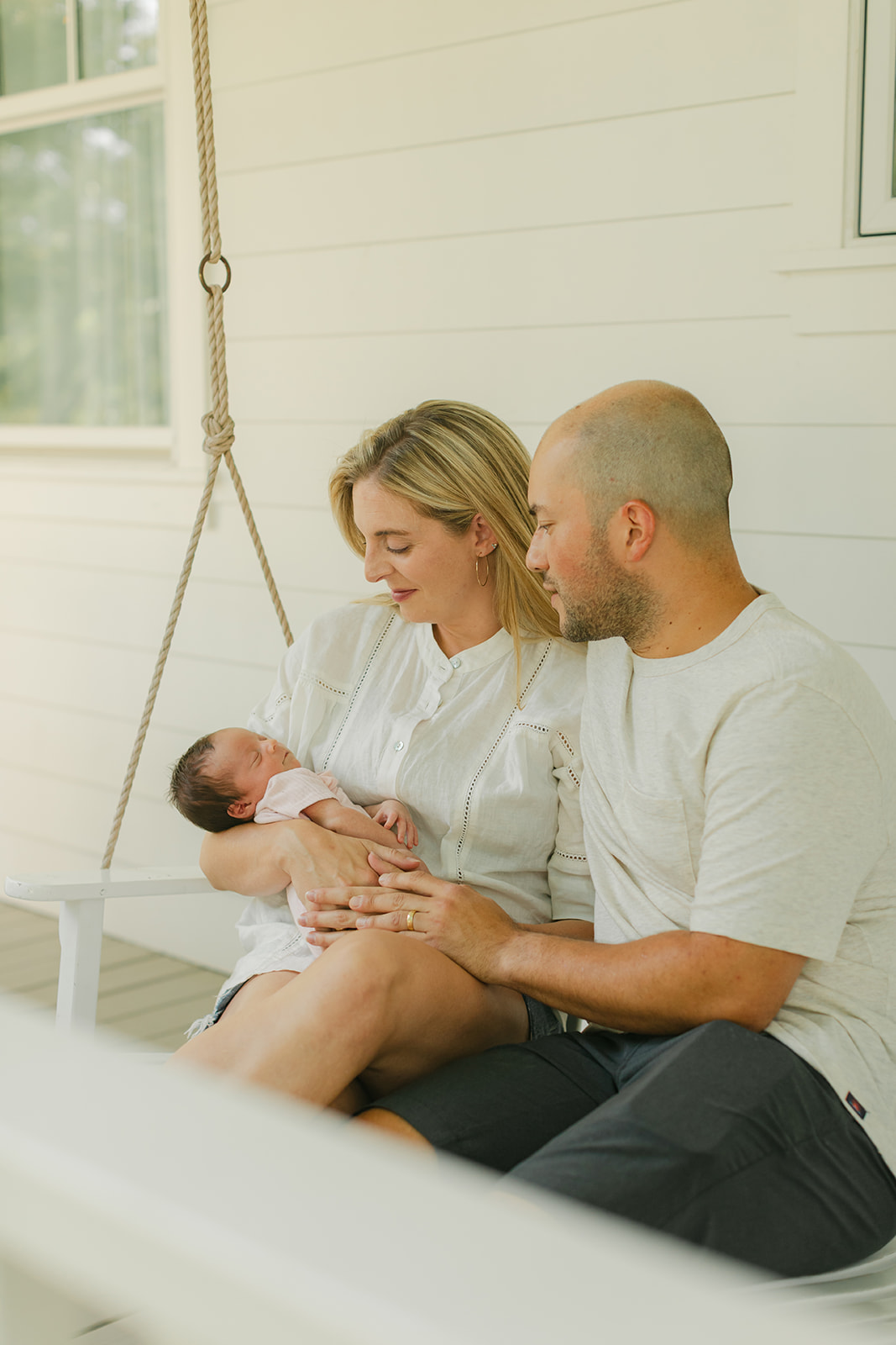 parents with newborn baby girl in front porch