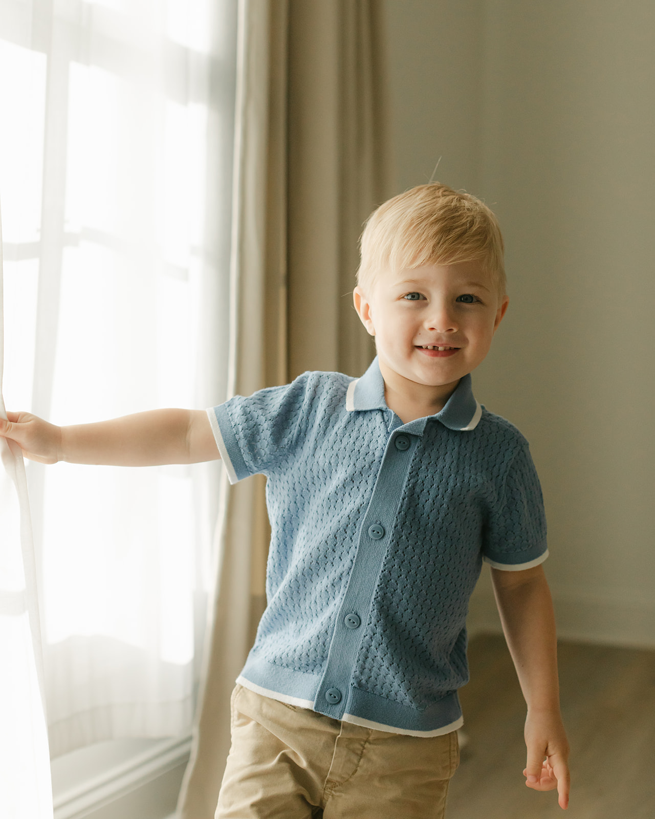 toddler boy standing by window