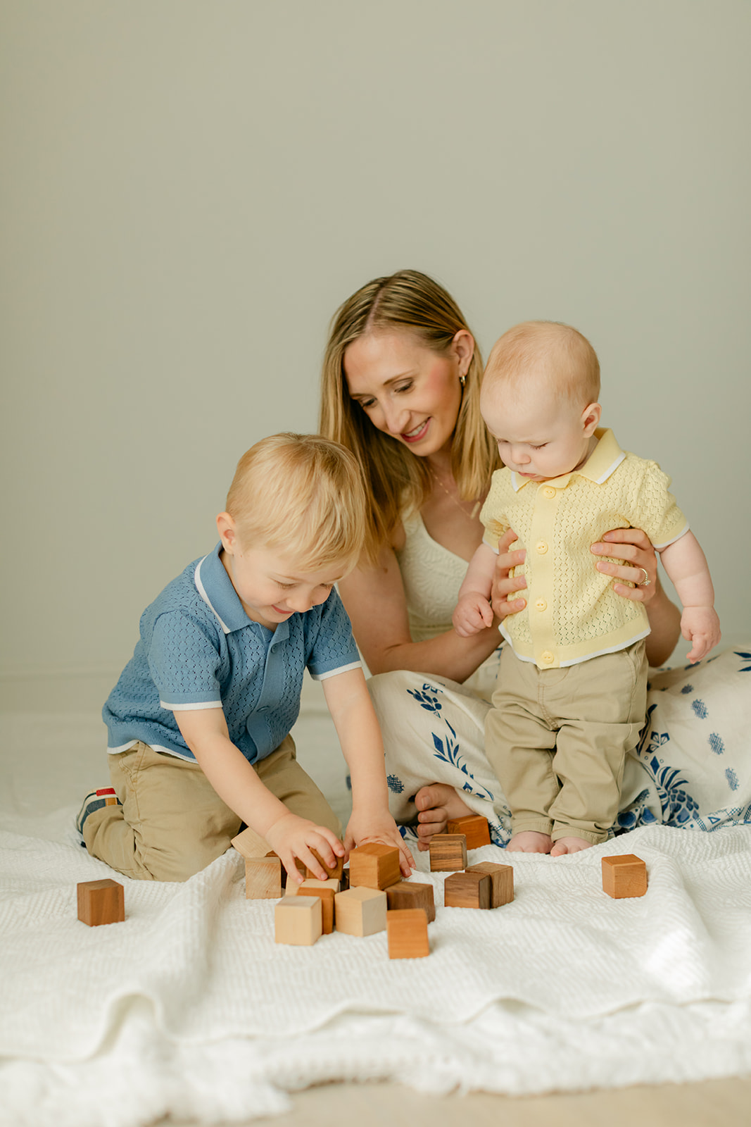mom and 6 month old baby boy and toddler boy playing with wood blocks
