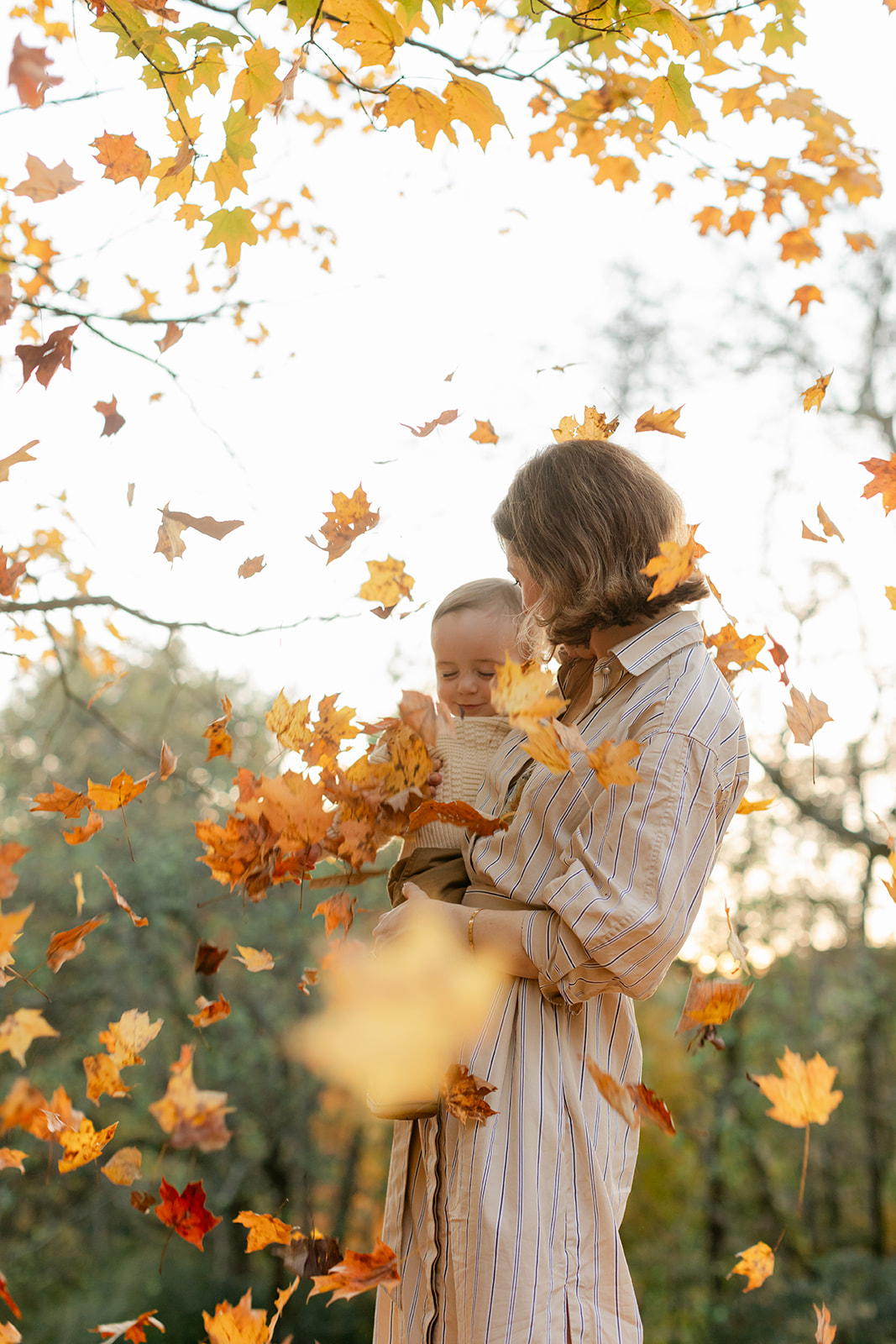 outdoor fall family session. mom and boy with falling leaves