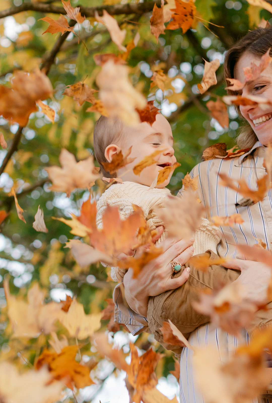 outdoor fall family session. mom and baby boy with falling leaves