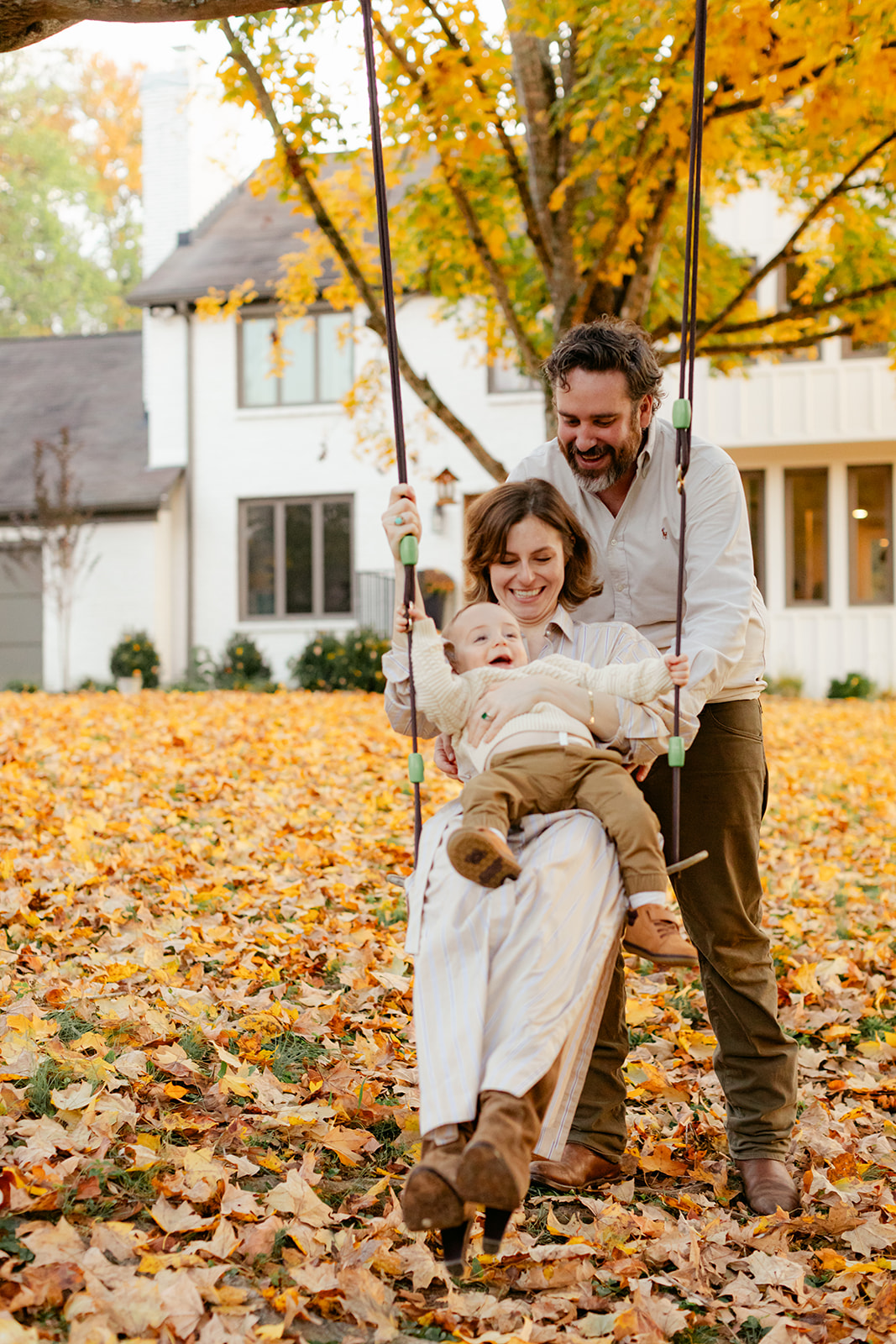 outdoor fall family session. mama sitting with son on swing and dad behind