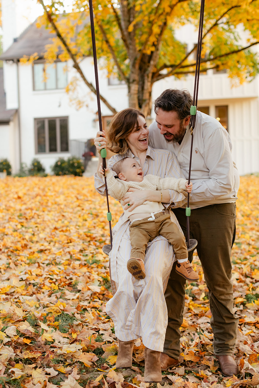 outdoor fall family session. mama sitting with son on swing and dad behind