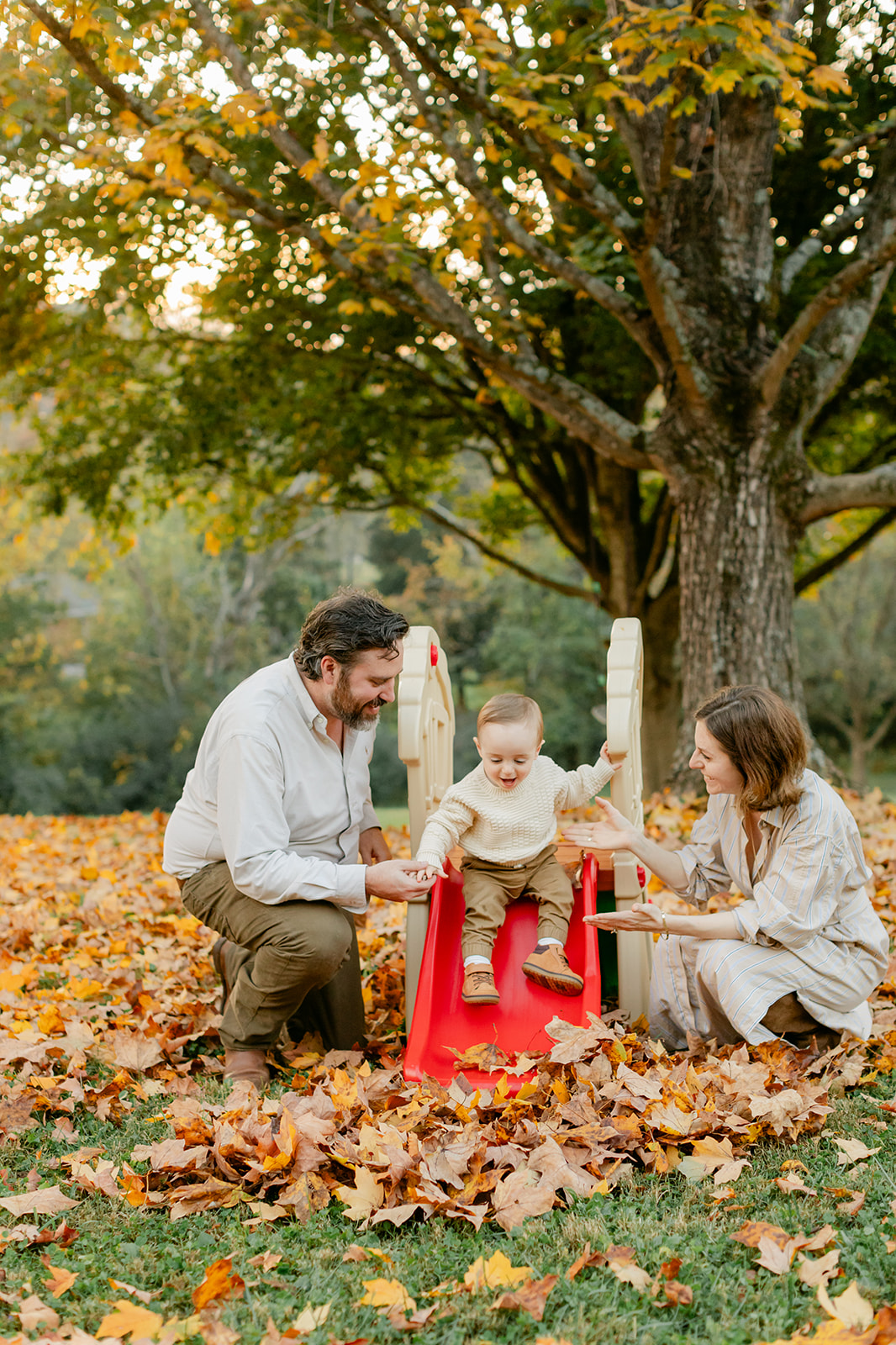 outdoor fall family session. little boy sliding on red slide