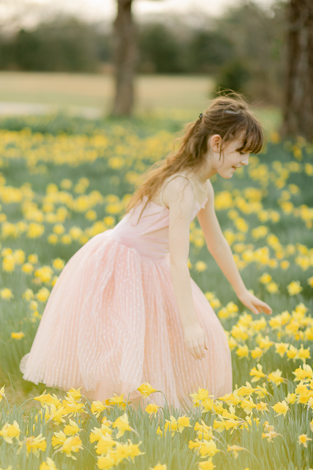 young girl in pink dress in daffodil field