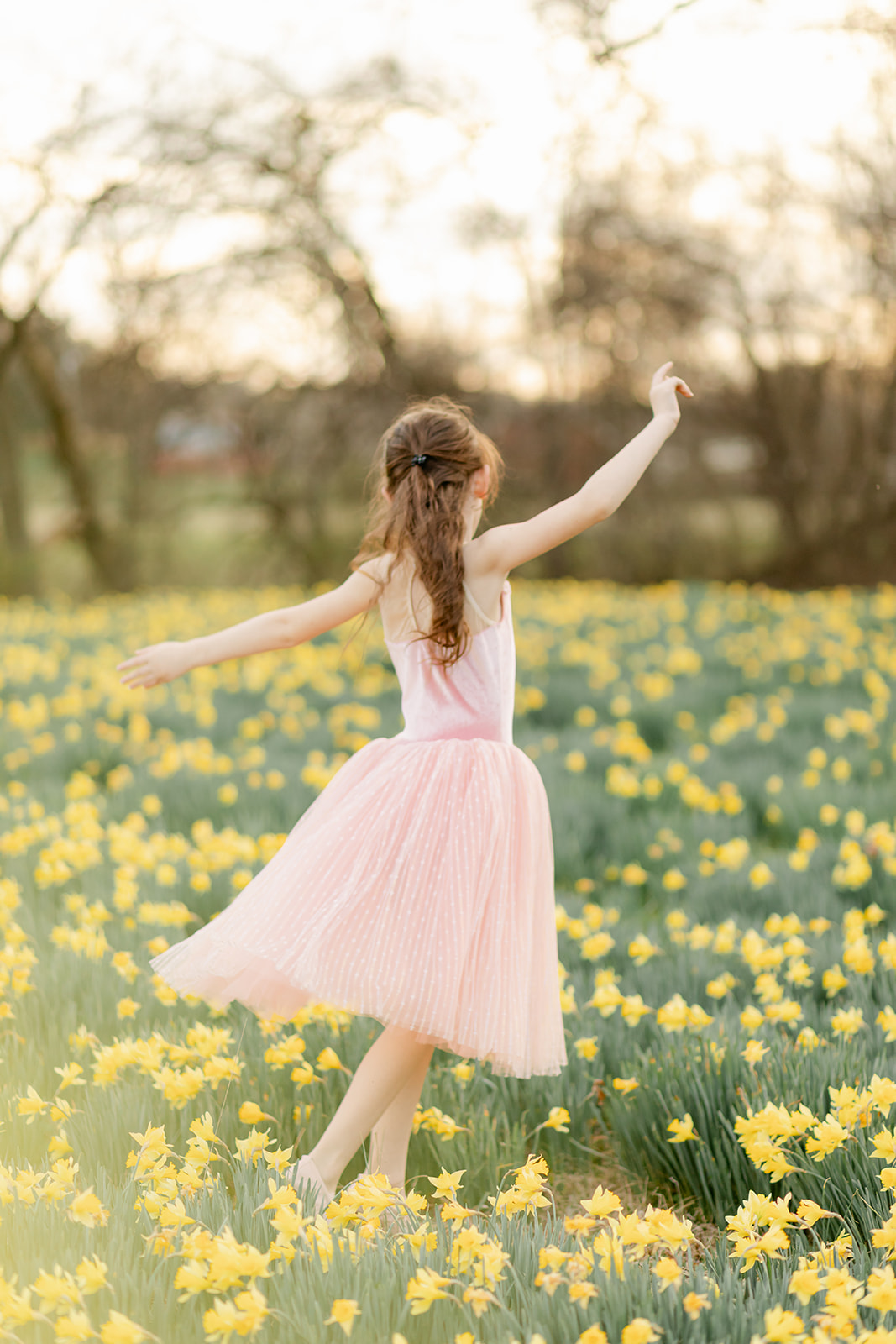 young girl in pink dress in daffodil field
