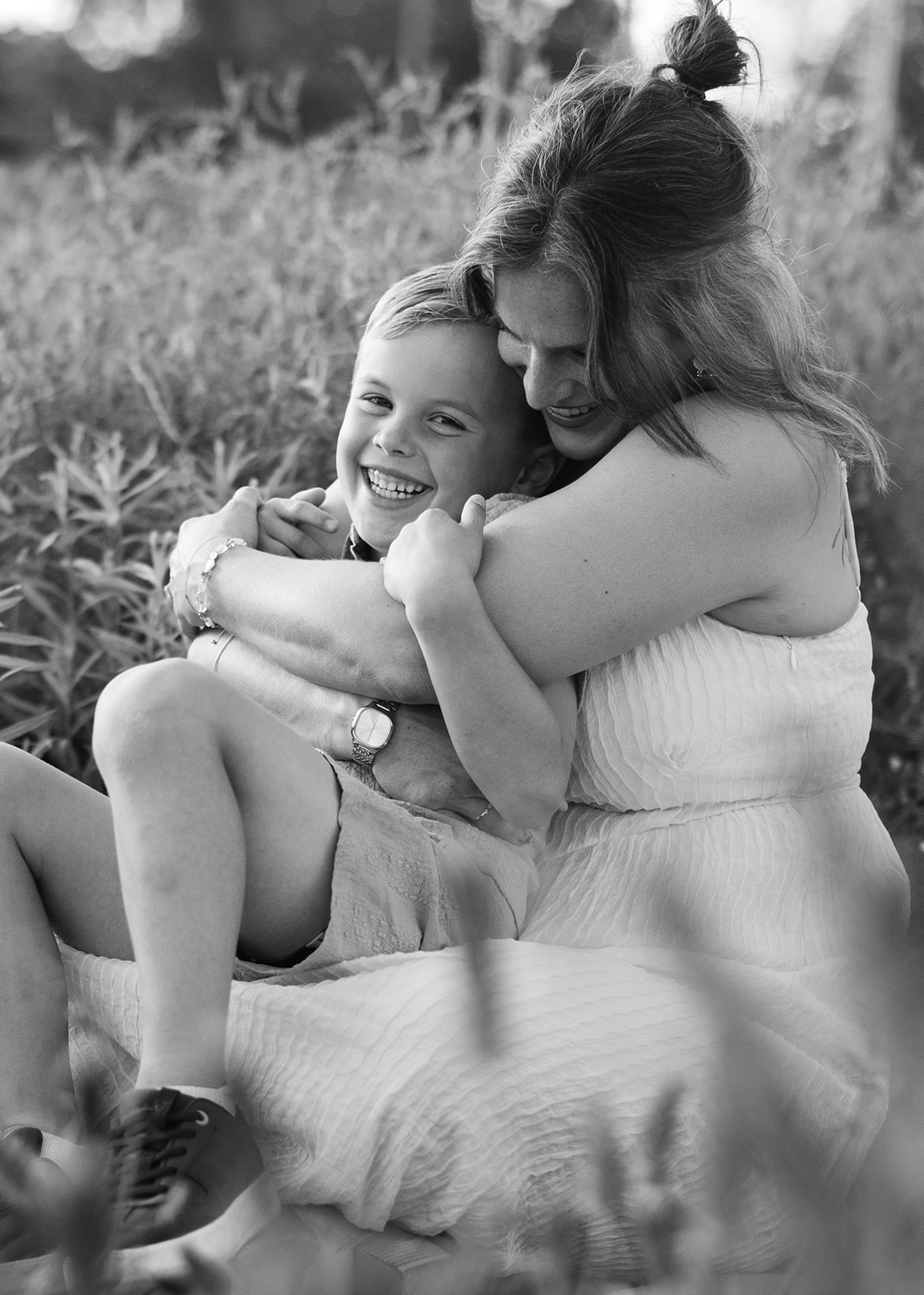 mother hugging son. Outdoor photo session in green field.