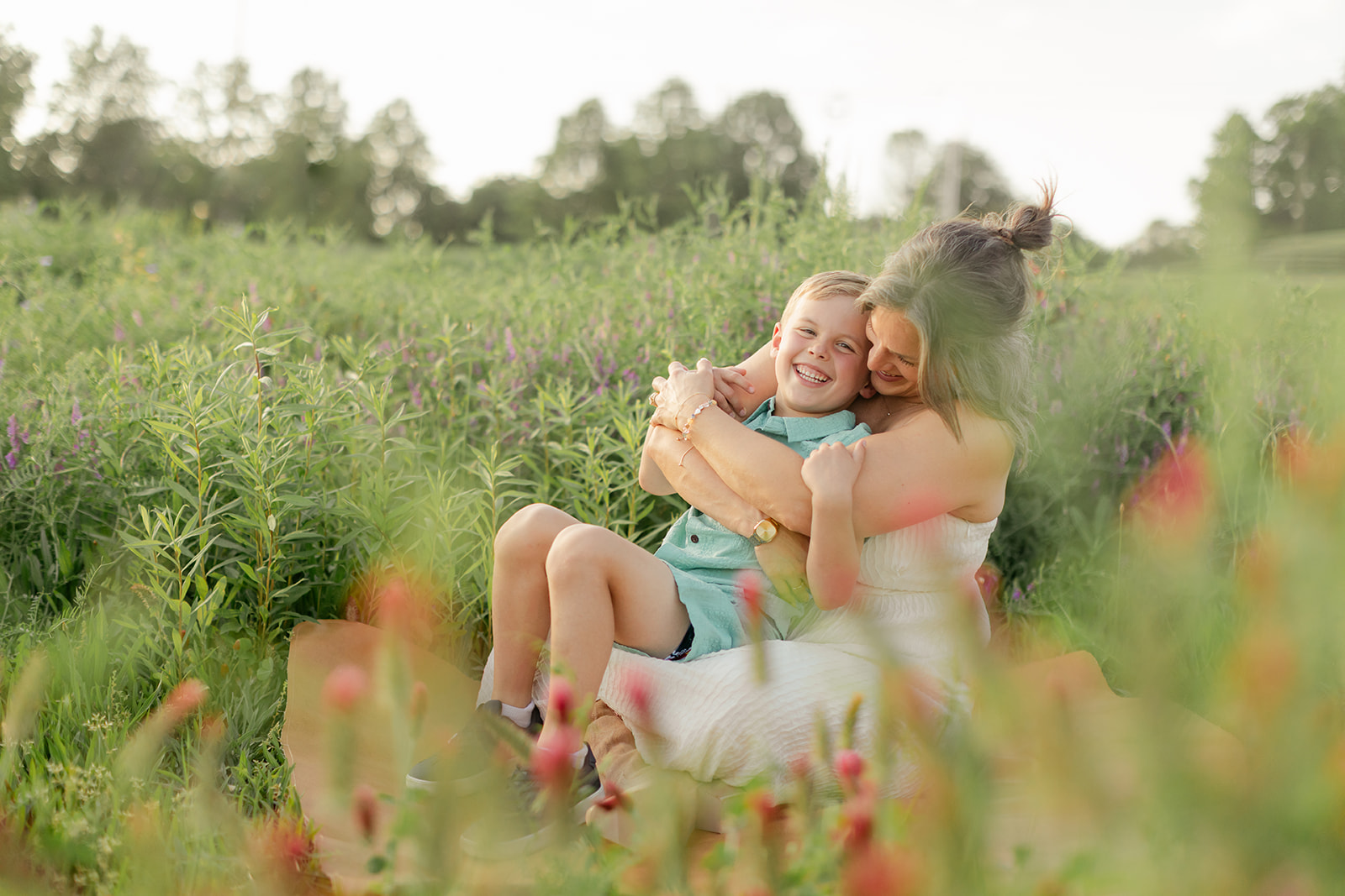 mama and son hugging. Outdoor photo session in green field.