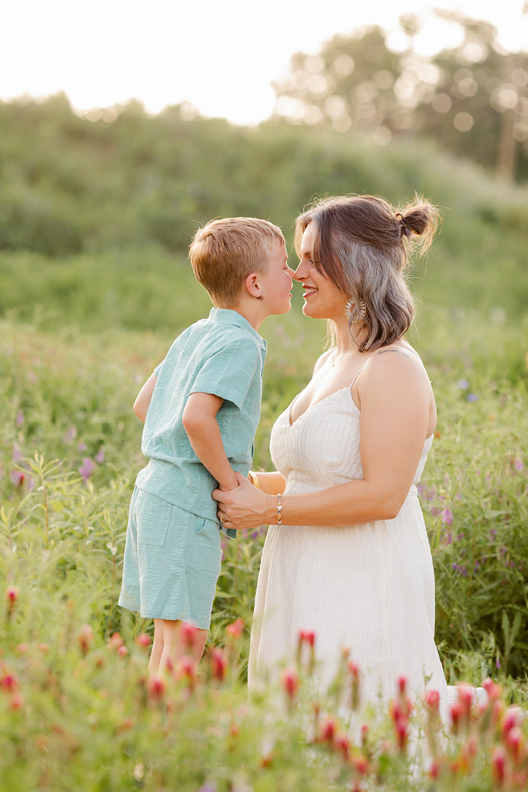 mama and son rubbing noses. Outdoor photo session in green field.