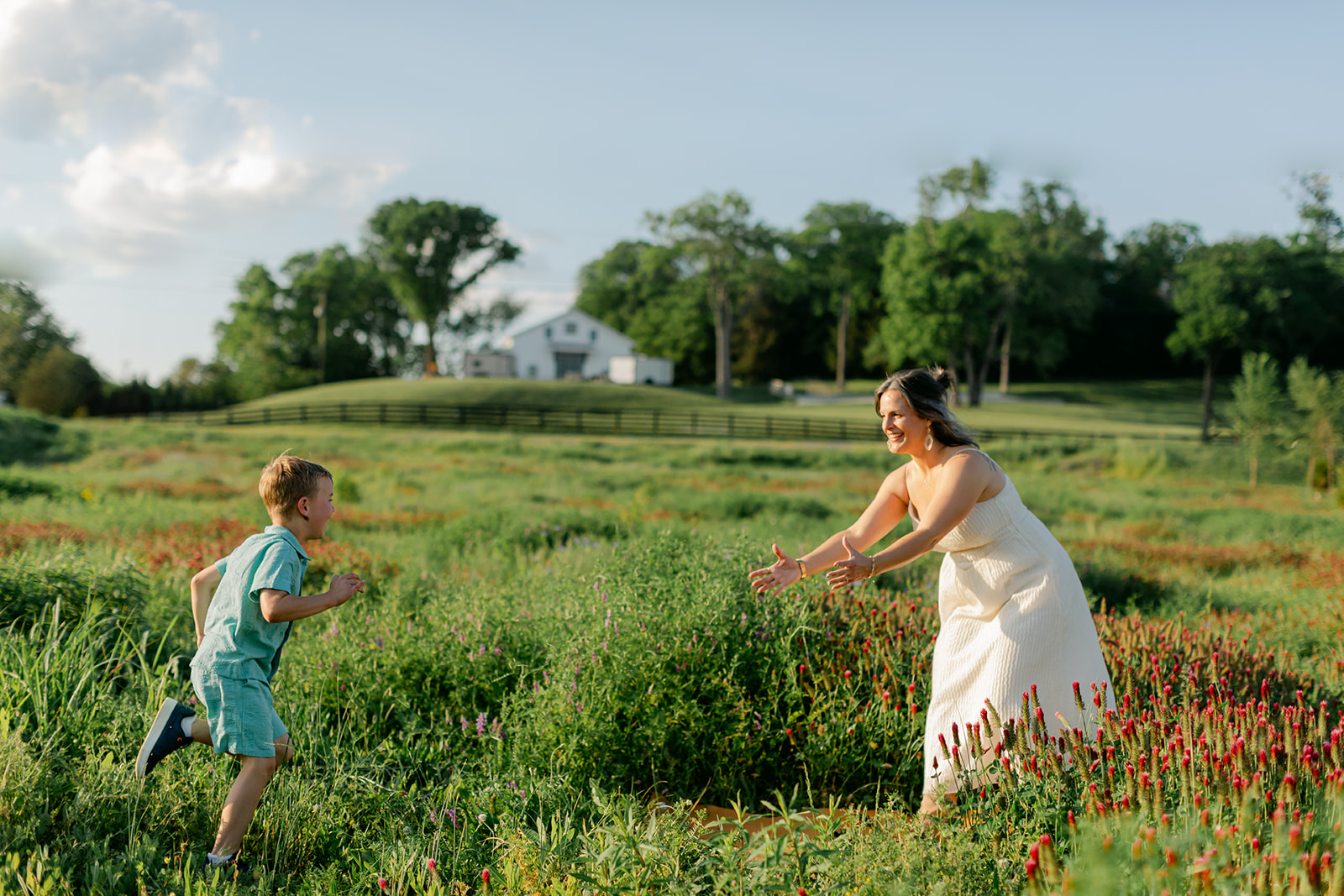 son running towards mom. Outdoor photo session in green field.