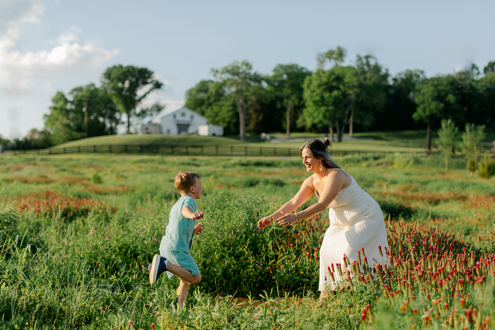 son running towards mom. Outdoor photo session in green field.