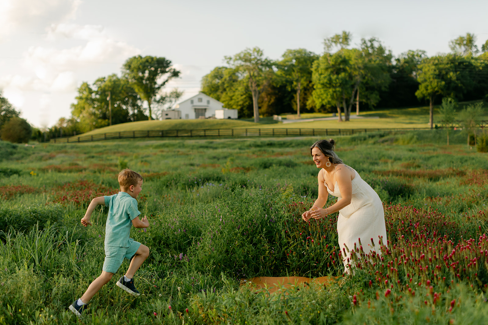 son running towards mom. Outdoor photo session in green field.